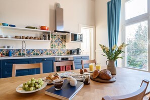Eine Küche mit Esstisch, gedeckt für das Frühstück, mit Brot, Eiern und Obst.