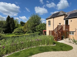 Ein Haus mit Garten, einer Holztreppe und Solaranlage auf dem Dach.