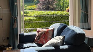 A room with a sofa facing a large window with a view of a garden. - Artist's Studio (sleeps 2) - Piddlehinton, Dorchester, sleeps 2 guests  in 1 bedroom (Piddlehinton)