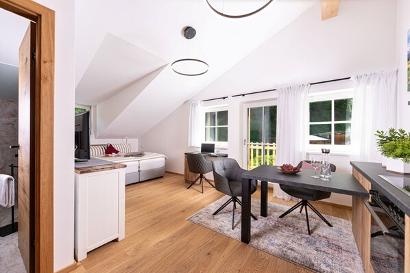 A modern kitchen with a dining area, a built-in oven, and a large window with curtains. - Vrbo Property (Schönau am Königssee)
