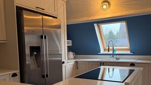 Une cuisine moderne dotée d’un réfrigérateur encastré, d’un évier et d’une lucarne.