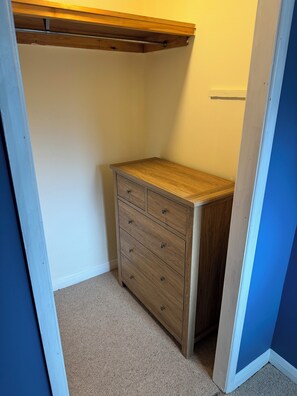 Ein kleiner, abgeschlossener Raum mit einem Holzschrank, Ablagefläche unter der Decke und Teppichboden.