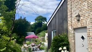 En bygning med murstensfacade, hvid stakit og en terrasse med udendørs møbler.