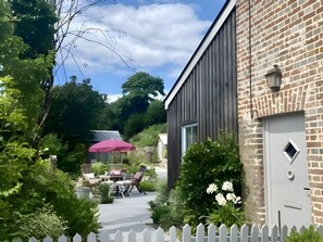A building with a brick facade, a white picket fence, and a patio area with outdoor furniture. - Foxearth (Sleeps 2) - Winterborne Houghton, Dorset (Blandford Forum)