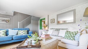 En stue med en blå sofa, en hvid sofa og et sofabord med bøger og en bakke.