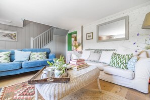 A living room with a blue sofa, white sofa, and a coffee table with books and a tray. - Foxearth (Sleeps 2) - Winterborne Houghton, Dorset (Blandford Forum)
