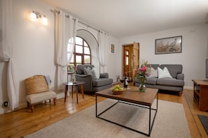 A living room with two grey sofas, a wooden coffee table, a wicker chair, and a small side table. - Chantry Cottage (Sleeps 4) -  Beaminster, Dorset (Chard, Beaminster)