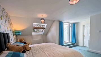 Un dormitorio con cama, ventana, un osito de peluche y un radiador.