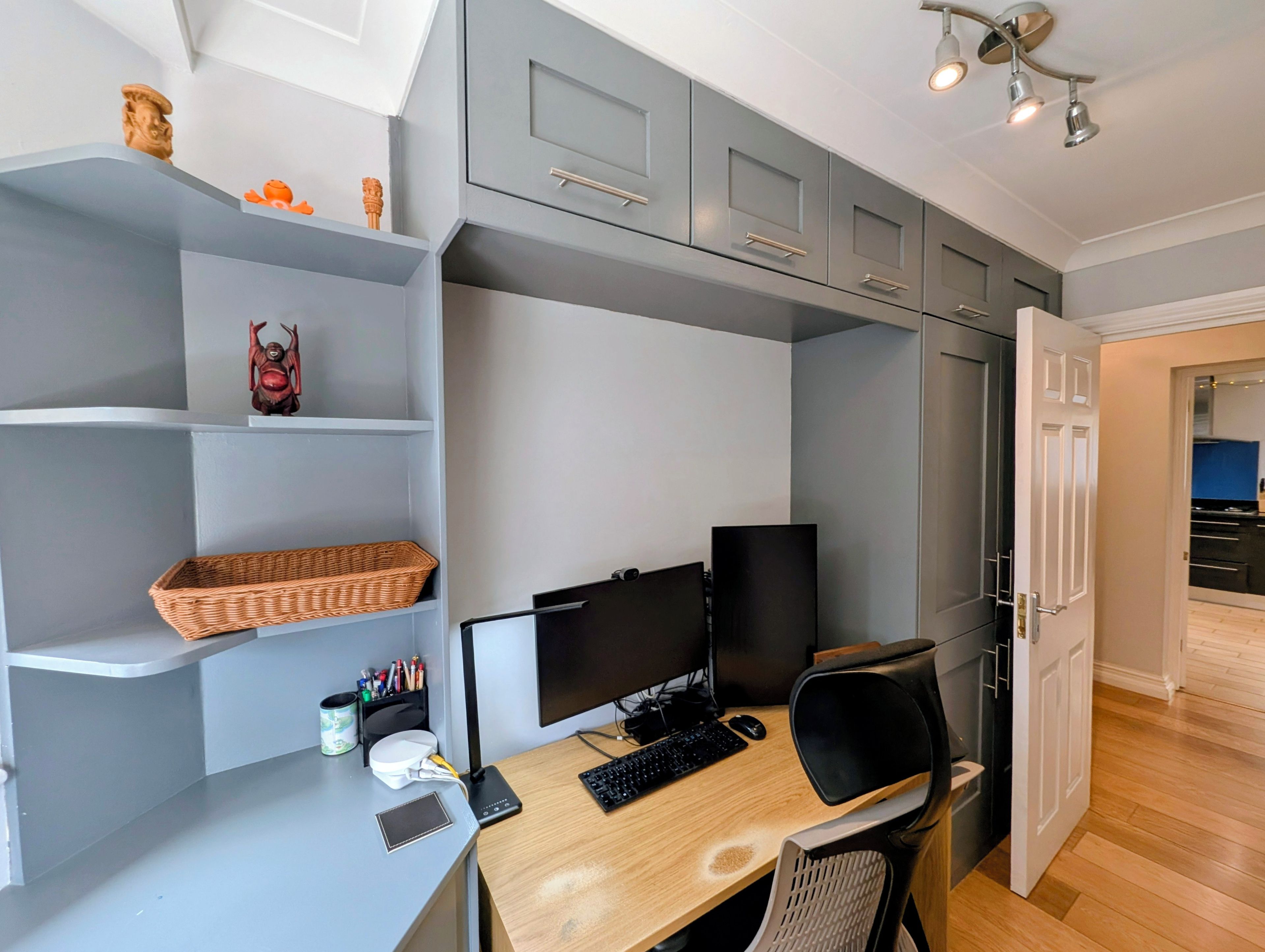 A modern office space with a desk, computer, and shelves.