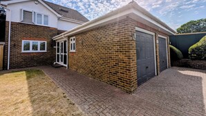 En boligejendom med murstensfacade, garageport og en belagt indkørsel.
