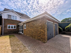 A residential property with a brick exterior, a garage door, and a paved driveway. - Stylish 5BDR Retreat with Parking and Fast WiFi (Greater London)