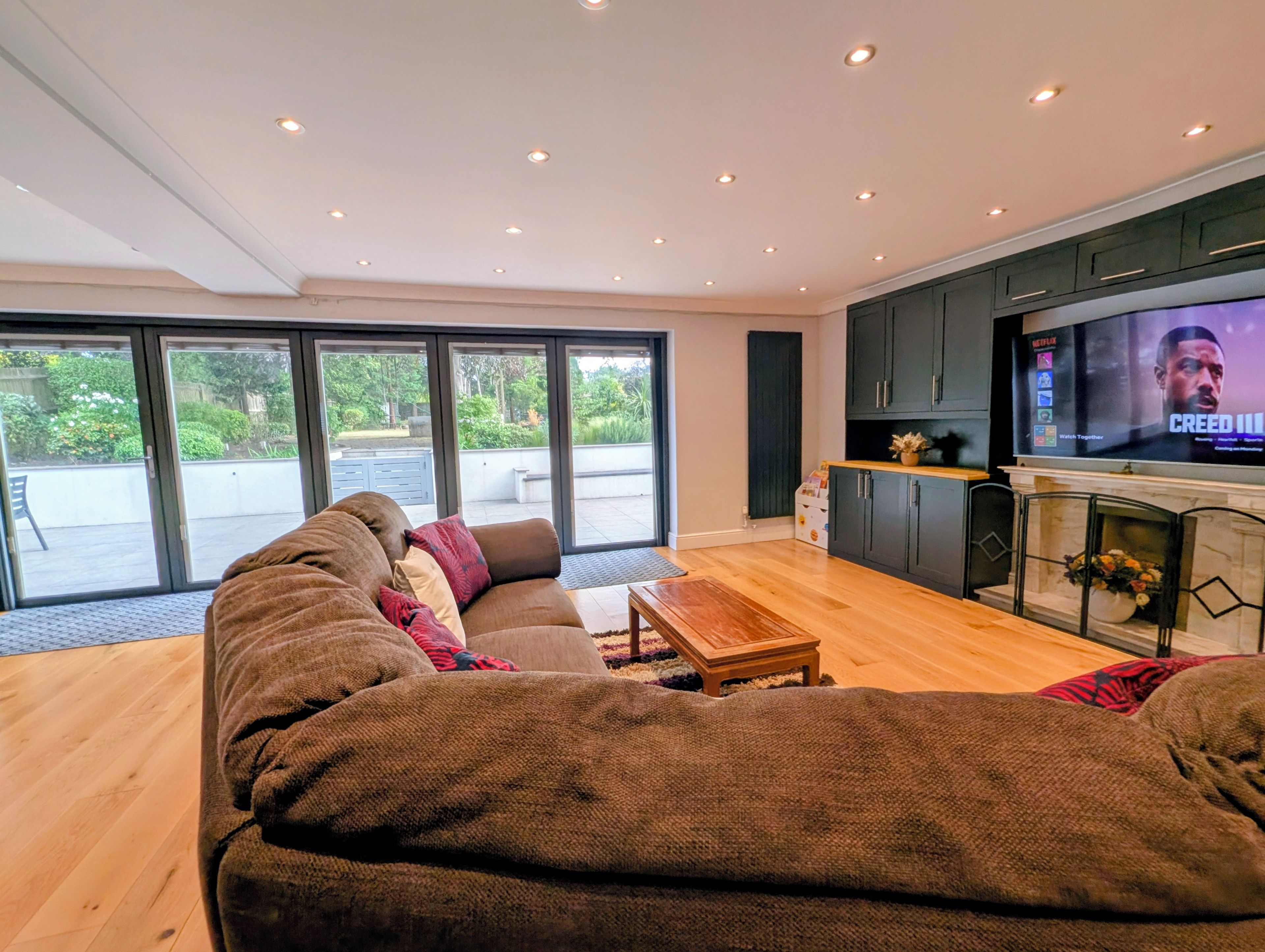 A modern living room with a large sofa, a coffee table, and a television on a stand.