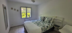 Ein Schlafzimmer mit Bett, Fenster, Heizkörper und Sessel.