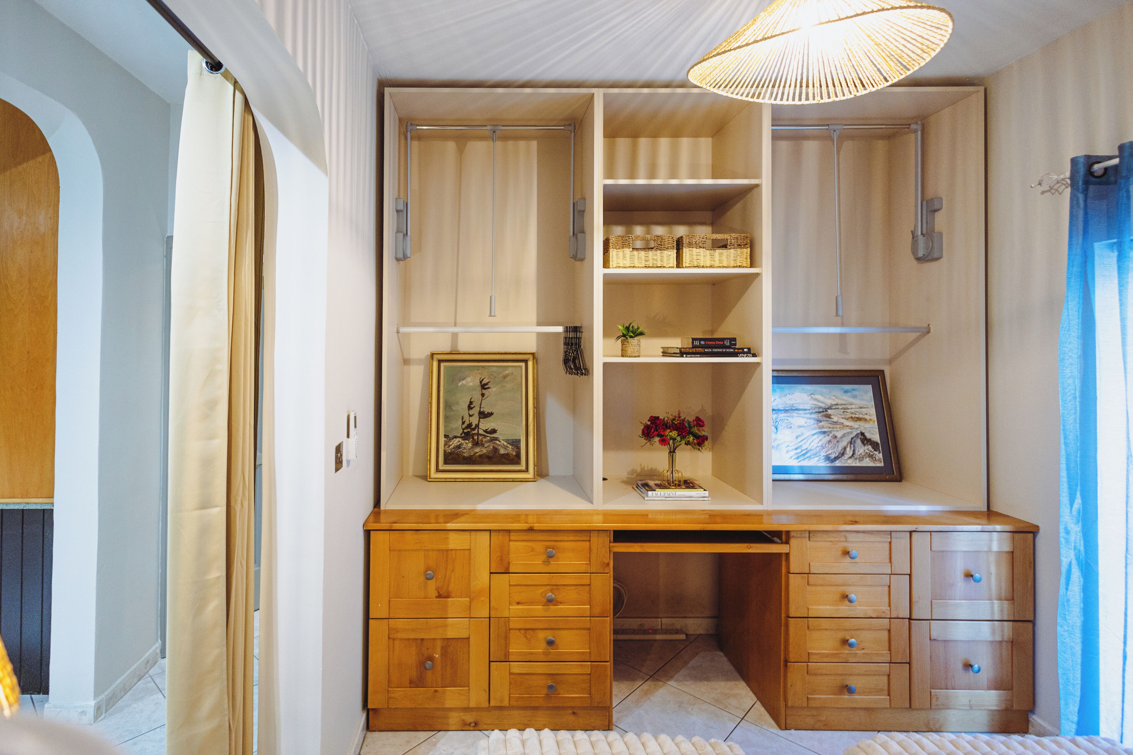 Quarto compacto com escrivaninha integrada, prateleiras e luminária pendente.