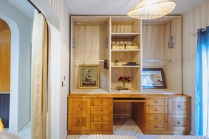 Quarto compacto com escrivaninha integrada, prateleiras e luminária pendente.