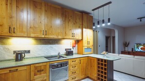 A kitchen with wooden cabinets, a built-in oven, a coffee maker, and a wine rack. - Three bedroom Apartment (Il-Gżira)
