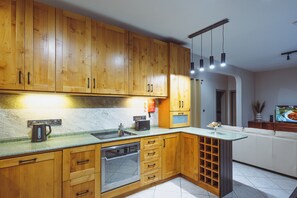 Cozinha com armários de madeira, forno embutido, cafeteira e adega.