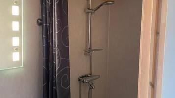 A shower with a curtain, a wooden ceiling, and a white sink.