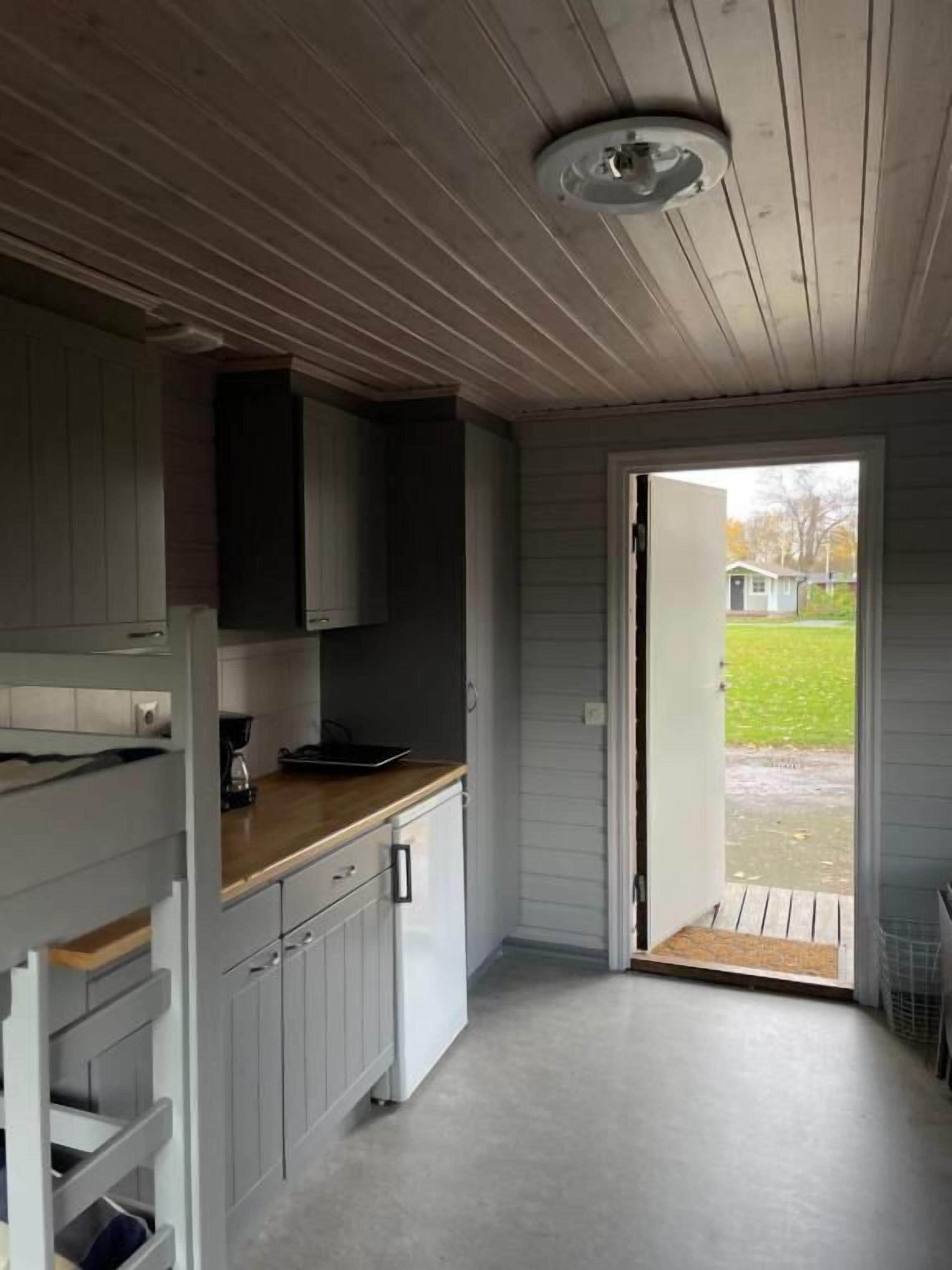 A kitchen with white cabinets, a wooden countertop, and a door leading outside.