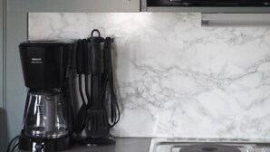 A kitchen with a coffee maker, a microwave, and a marble backsplash. - Skara Stadscamping & Stugby (Skara)