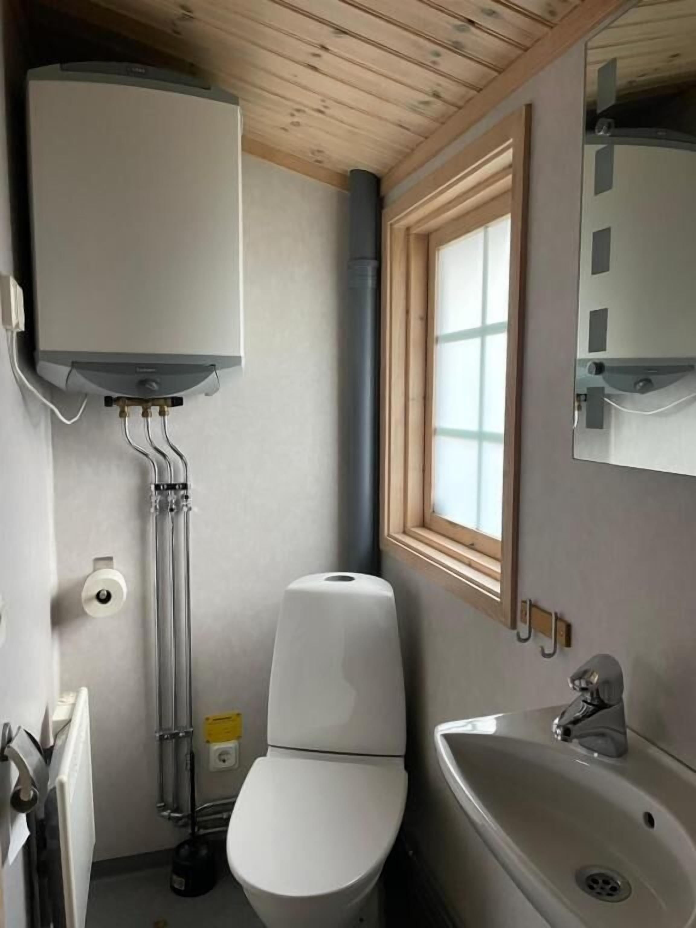 Une petite salle de bain comprenant des toilettes, un lavabo et une fenêtre.