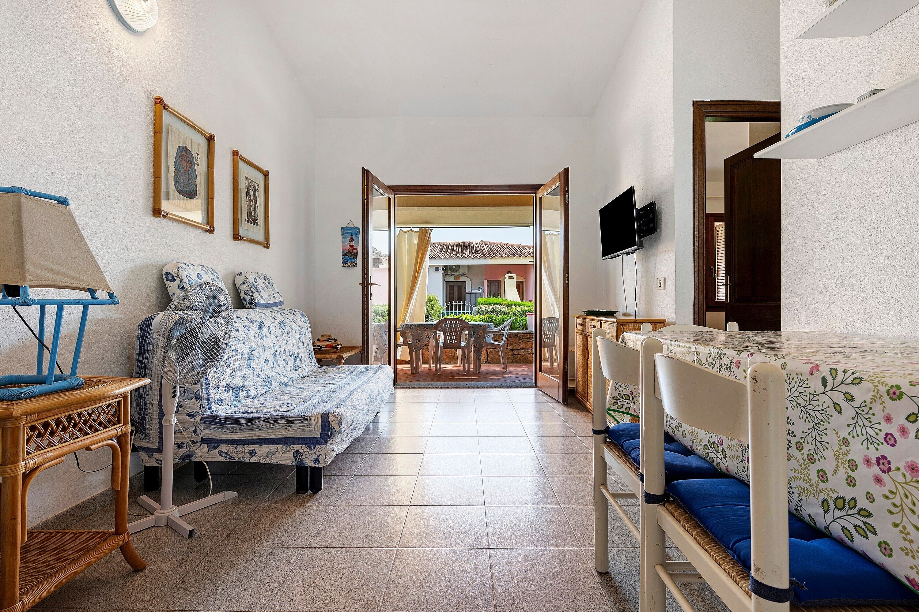 A room with a bed, a chair, a table, and a television.