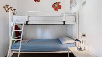 Een stapelbed met een ladder, een klein nachtkastje met een lamp en wanddecoraties.
