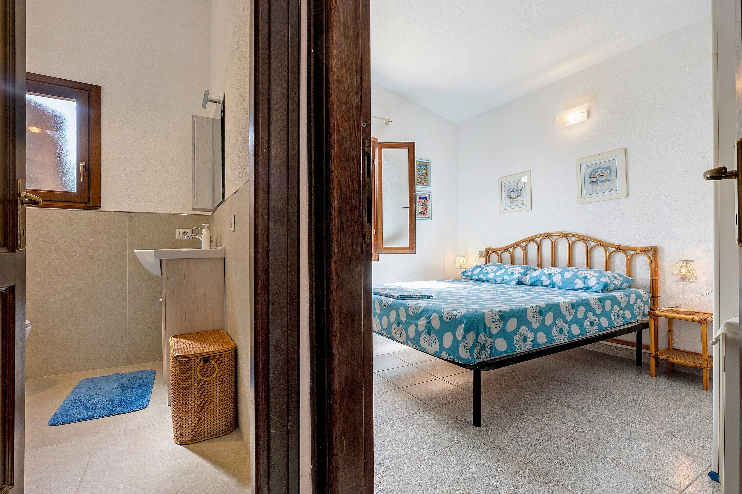 Un dormitorio con cama, mesita de noche, lámpara y un cuadro colgado en la pared.