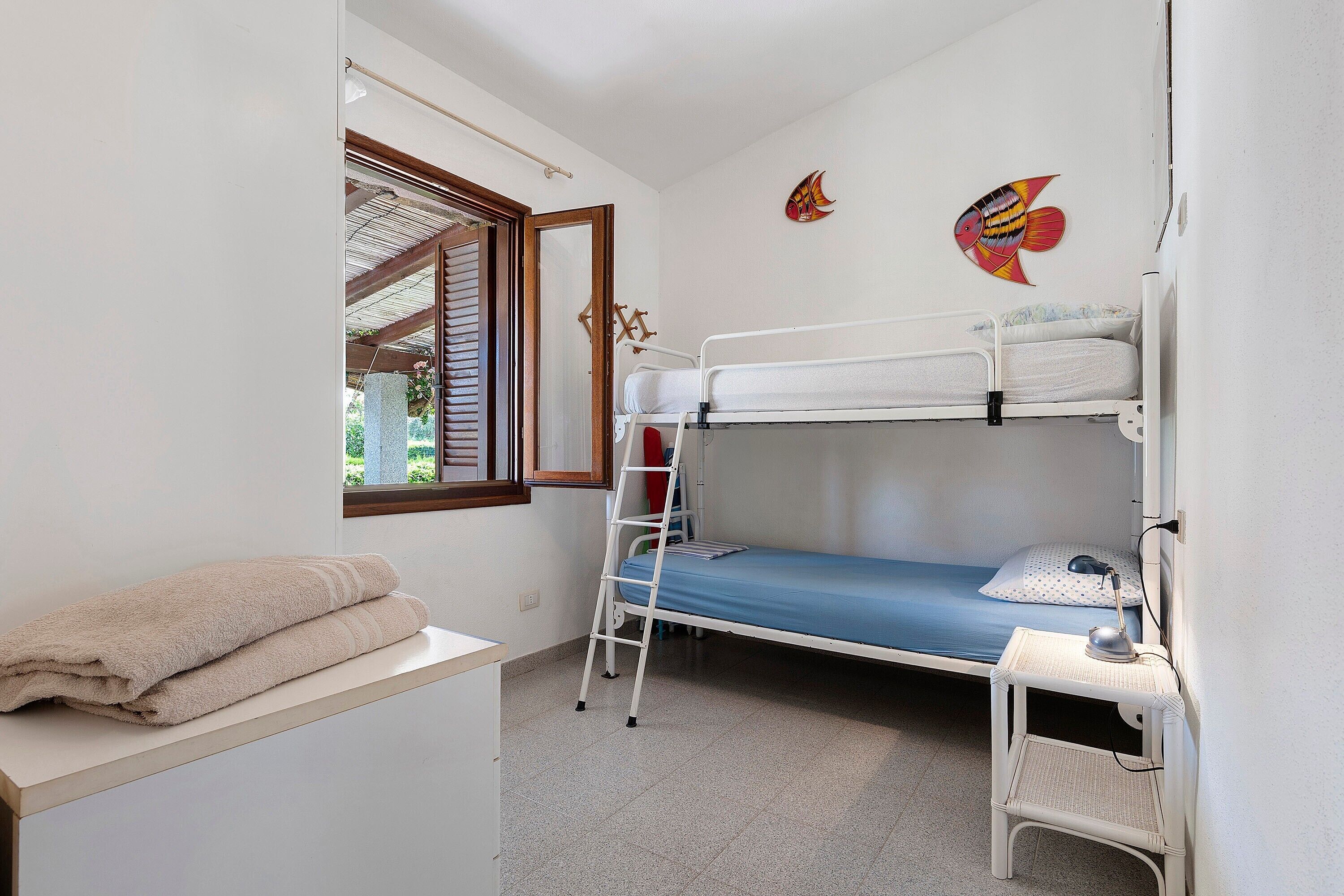 Una camera con un letto a castello, una scrivania e una sedia, con una finestra.