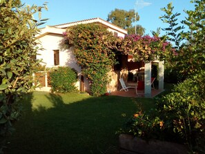 A house with a garden, a patio with chairs, and a clear sky. - Holiday Home 'Gli Oleandri' with Private Terrace and Garden (San Teodoro)