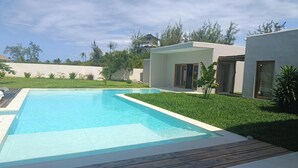 A modern pool area with a clear blue pool, wooden deck, and a well-maintained lawn. - Stunning newly built villa located 50 meters from Fortamu Beach (Watamu)