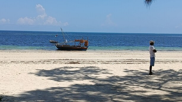 A beach with a boat and a person standing on the sand. - Stunning newly built villa located 50 meters from Fortamu Beach (Watamu)