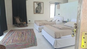 A bedroom with two beds, a colorful rug, a framed picture on the wall, and a chair. - Stunning newly built villa located 50 meters from Fortamu Beach (Watamu)
