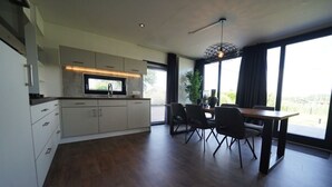 A modern kitchen with a dining area, large windows, and a view of the outdoors. - Cube Magnifique 6 (Nijkerk)