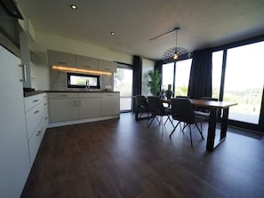 A modern kitchen with a dining area, large windows, and a view of the outdoors. - Cube Magnifique 6 (Nijkerk)