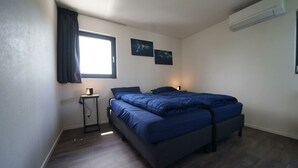 A bedroom with a bed, a bedside table, a lamp, a window with curtains, and two wall-mounted pictures. - Cube Magnifique 6 (Nijkerk)