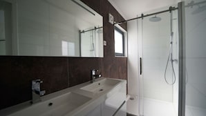 A modern bathroom with a large mirror, two sinks, a shower, and dark marble walls. - Cube Magnifique 6 (Nijkerk)