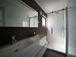A modern bathroom with a large mirror, two sinks, a shower, and dark marble walls. - Cube Magnifique 6 (Nijkerk)