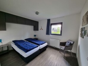 A bedroom with a bed, a chair, a desk, a radiator, and a window. - Cube Magnifique 10 (Nijkerk)