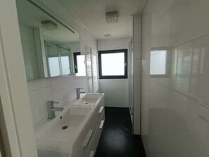 A modern bathroom with a large mirror, a sink, and a window. - Cube Magnifique 10 (Nijkerk)