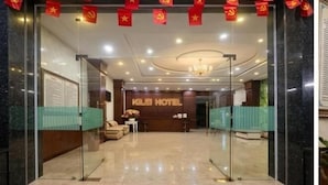 A hotel lobby with a reception desk, a chandelier, and red flags.