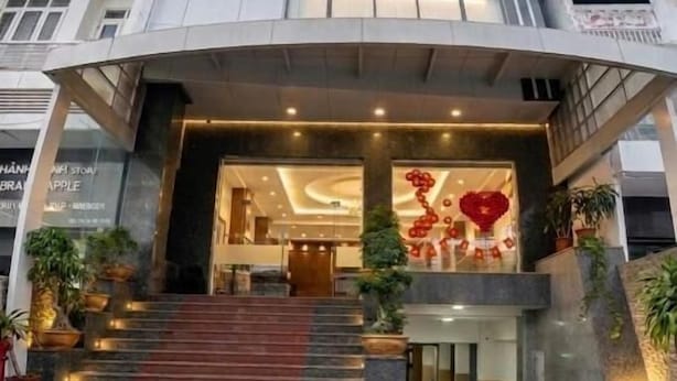 Un hotel con diseño moderno, que presenta una entrada destacada con escalones, fachada de vidrio y un letrero con el nombre.