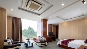 A hotel room with a sofa, a bed, a TV, and a large window.