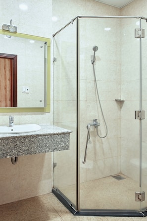 A bathroom with a glass-enclosed shower, a granite countertop sink, and a mirror with a wooden frame. - Klei Buon Ma Thuot City Centre (Buon Ma Thuot)