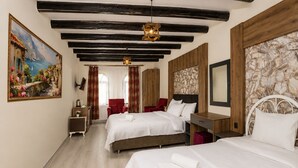 Habitación de hotel con dos camas, un cuadro, una pared de piedra y techo de madera.