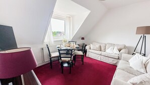 Ein Zimmer mit Esstisch, Stühlen, einer Couch, einer Lampe und einem Fenster mit Blick.