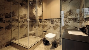 A modern bathroom with a glass-enclosed shower, a toilet, and a sink. - Europa  (Semey)