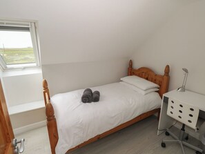 A single bed with a wooden headboard, a bedside table with a lamp, and a window with a view of the outdoors. - ISLANDS INN, pet friendly, with a garden in Louisburgh, County Mayo (Louisburgh)