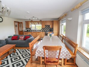 A compact living space with a dining table, a sofa, a kitchen area, and a window providing natural light. - ISLANDS INN, pet friendly, with a garden in Louisburgh, County Mayo (Louisburgh)