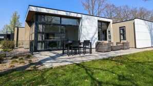 A modern house with large windows, a patio with outdoor furniture, and a small garden area. - Holiday Home in Nijkerk With Terrace (Nijkerk)